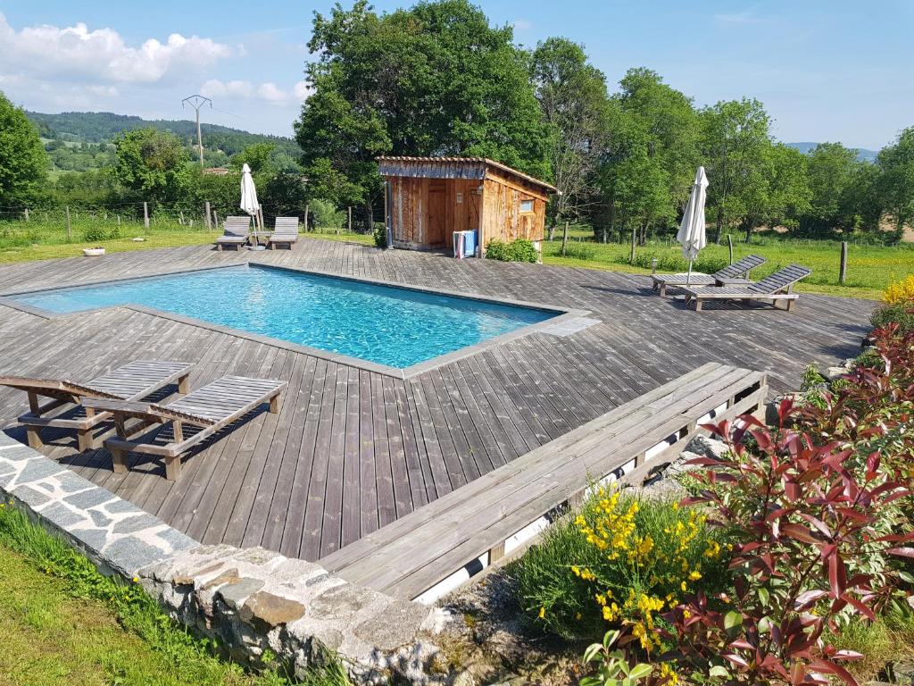 a swimming pool with two lounges and a wooden deck at Chambres et Table d'hôtes Il Fut Un Temps... in Saint-Marcel-dʼUrfé