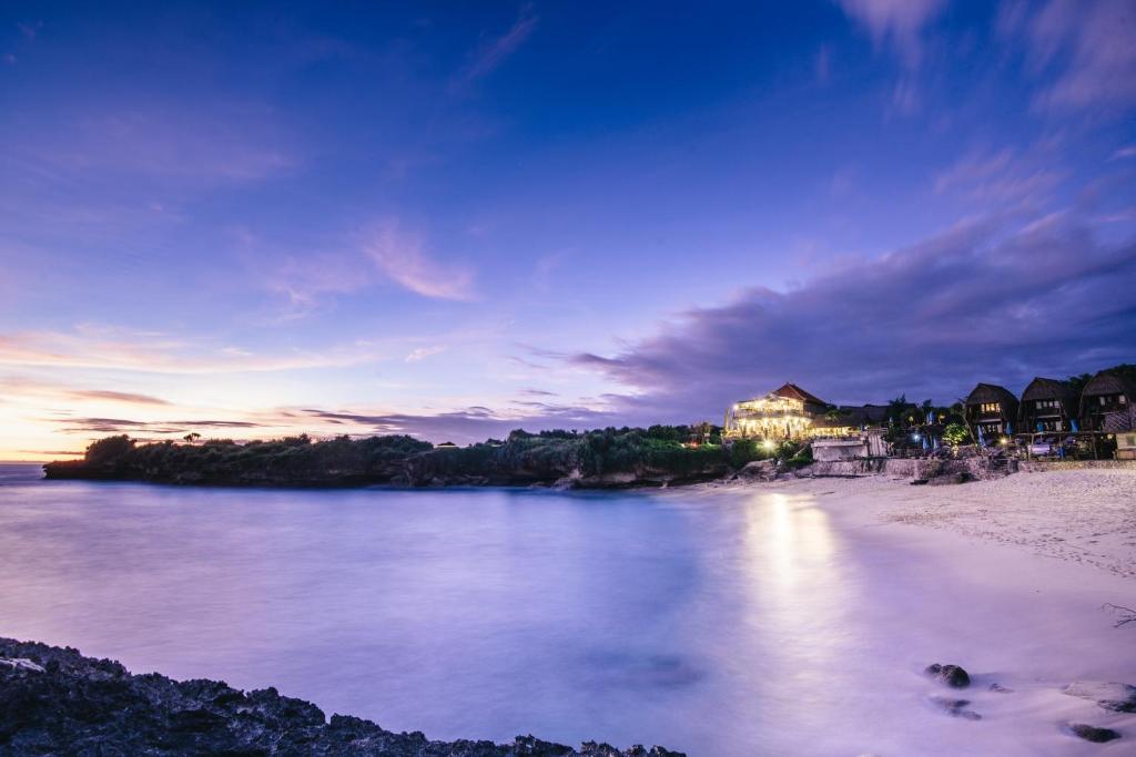 a view of a beach with a building in the distance at Dream Beach Huts in Nusa Lembongan
