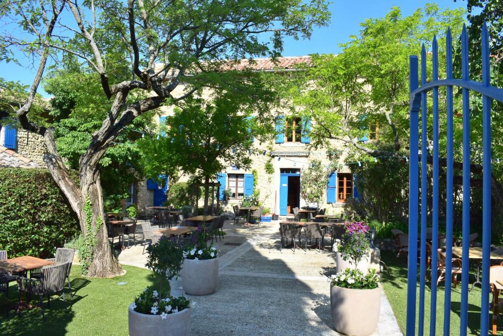 una puerta a un jardín con mesas y sillas en La Bastide Bleue, en Séguret