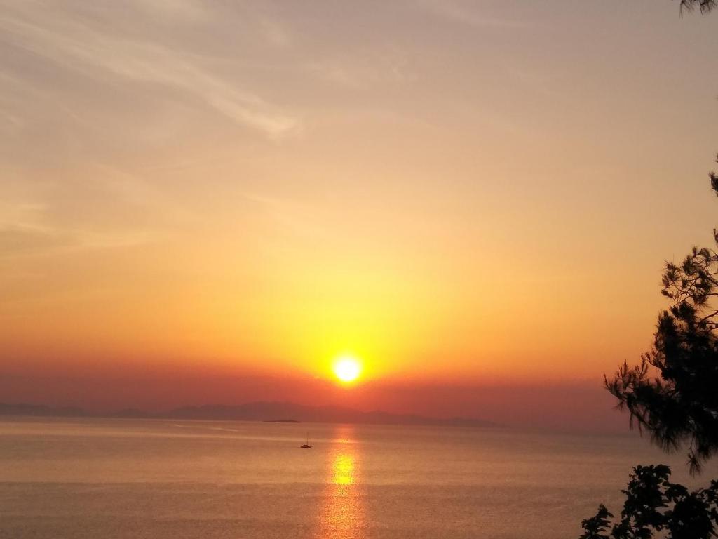 zachód słońca nad oceanem i słońce na niebie w obiekcie Kymi Bay House w mieście Platána