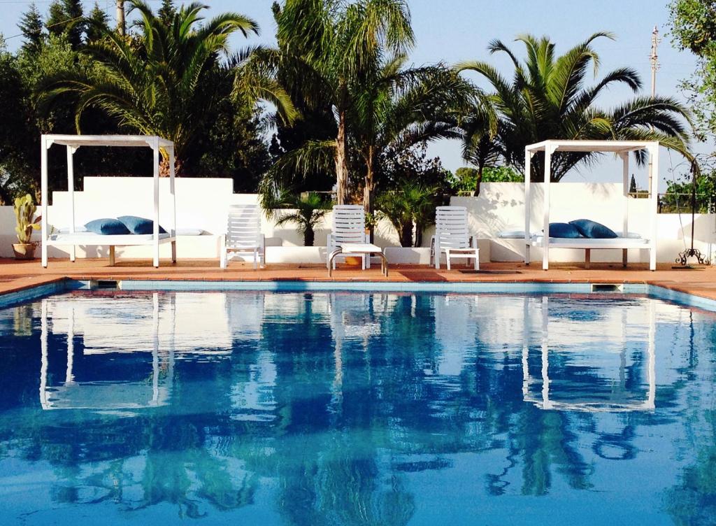 a swimming pool with white chairs and a swimming pool at Agriresidence Campi Latini in Galatone