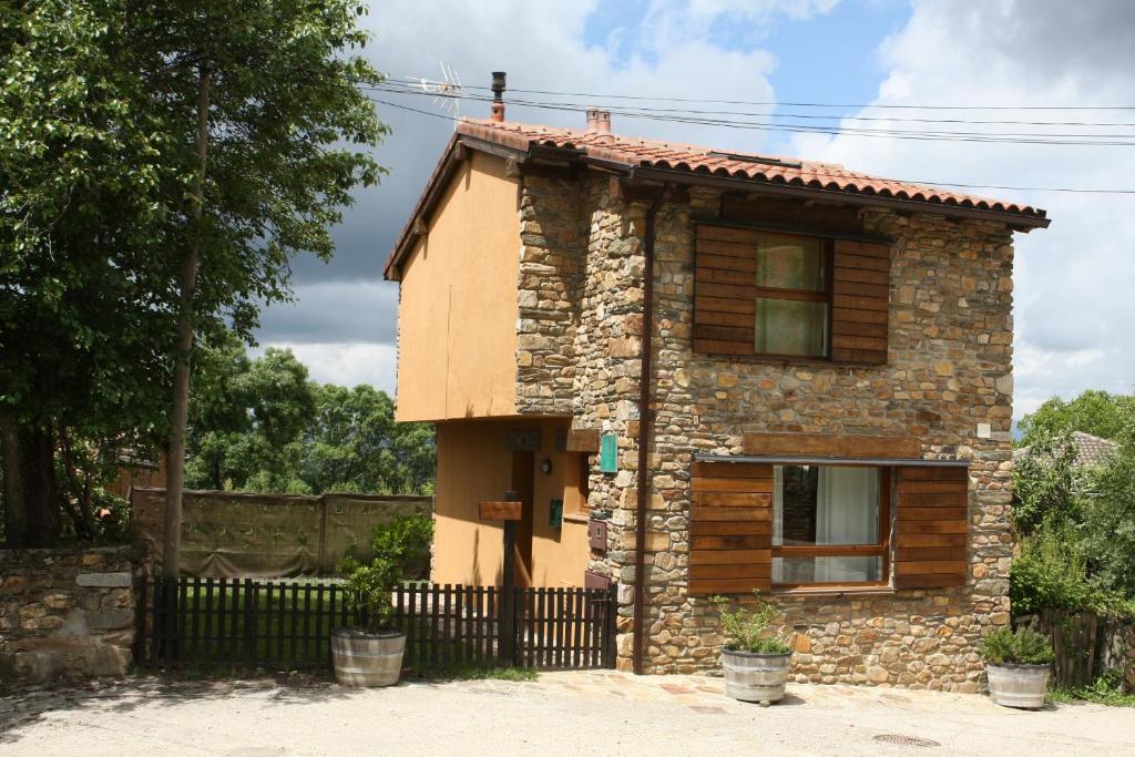 Campillo في Berzosa del Lozoya: منزل حجري صغير مع سور اسود