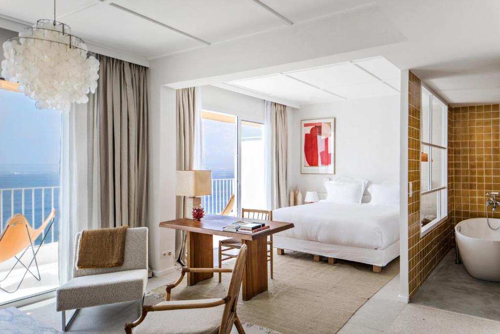 サン・ラファエルにあるLes Roches Rouges, a Beaumier hotelのベッド、デスク、バスタブが備わるホテルルームです。
