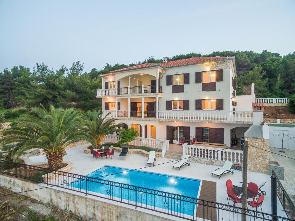 une grande maison avec une piscine en face de celle-ci dans l'établissement Villa Iž, à Veli Iž