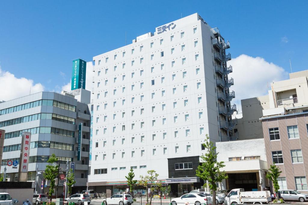 een wit gebouw met auto's ervoor geparkeerd bij Sanco Inn Shizuoka Kitaguchi in Shizuoka
