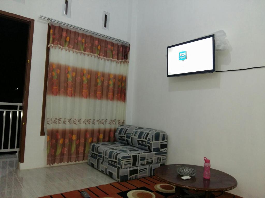 a living room with a couch and a flat screen tv at Penginapan Rezki Syariah in Bukittinggi