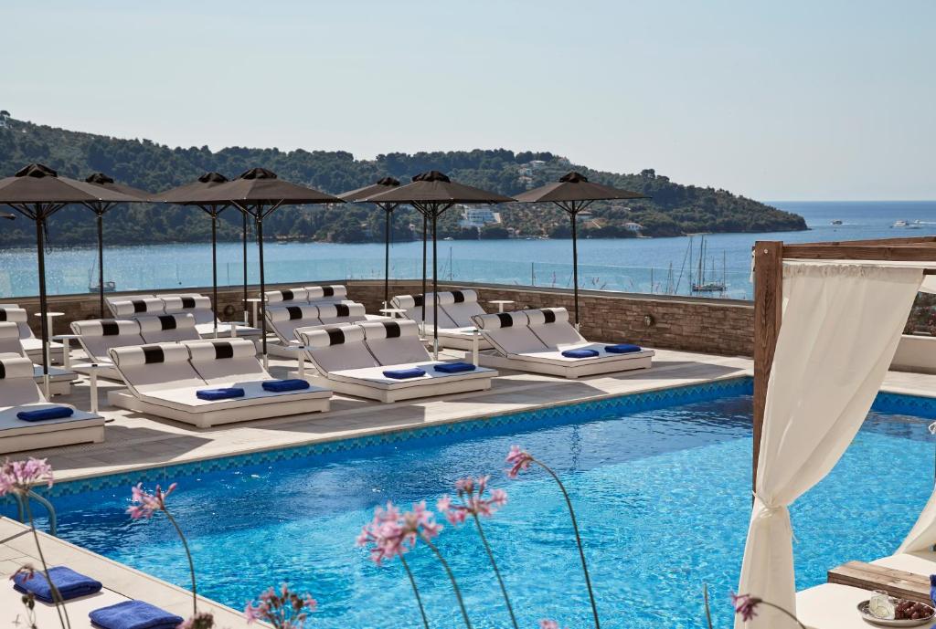 a pool with chairs and umbrellas next to the water at Skiathos Living in Skiathos Town