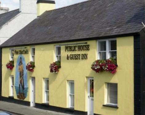 um edifício amarelo com um sinal na lateral em Finn MacCools Public House & Guest Inn em Bushmills