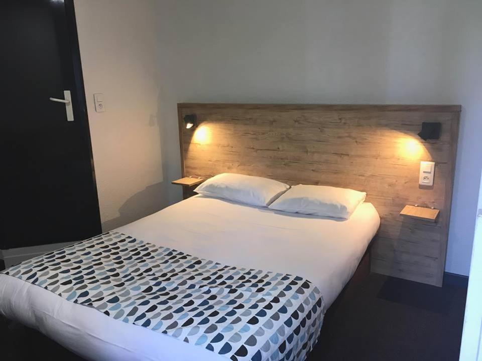 a bedroom with a large bed with a wooden headboard at my HOTEL Bordeaux in Artigues-près-Bordeaux