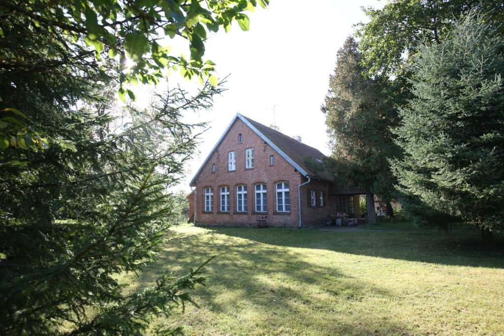 a large red brick house with trees in front of it at Mazurski dworek przy Jeziorze in Dworackie
