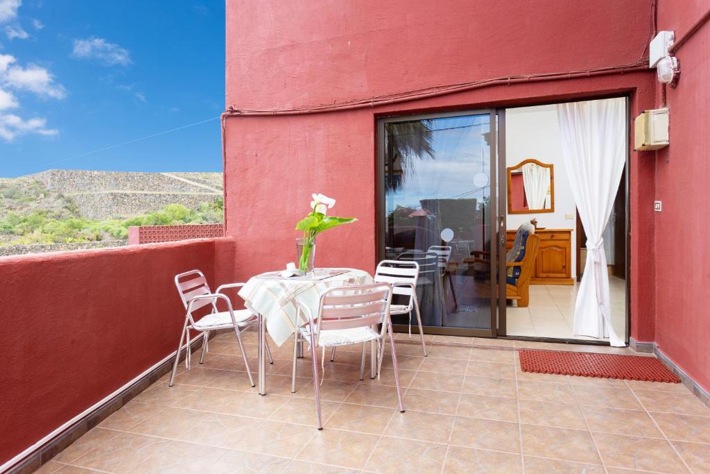 un patio con tavolo e sedie su una parete rossa di Finca La Gaviota - El Marmol a Icod de los Vinos