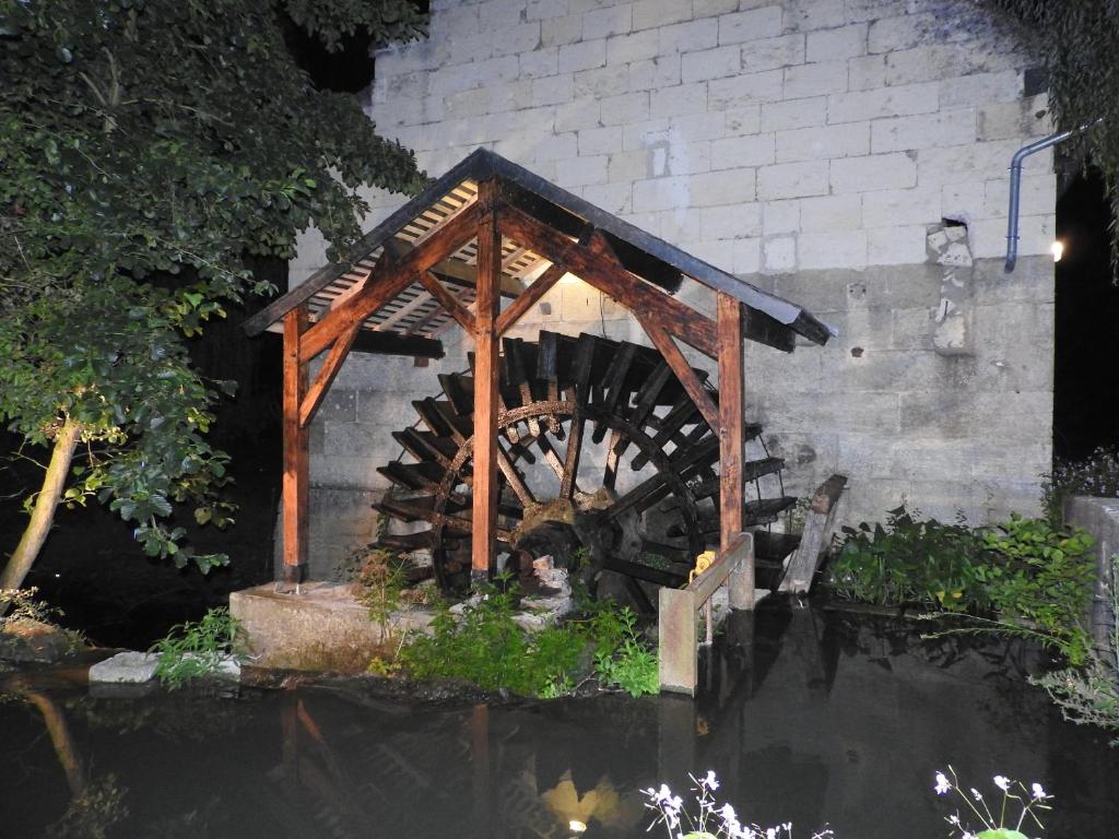 uma roda de água de madeira sentada no meio de um lago em Le Moulin De Saussaye em Crouzilles