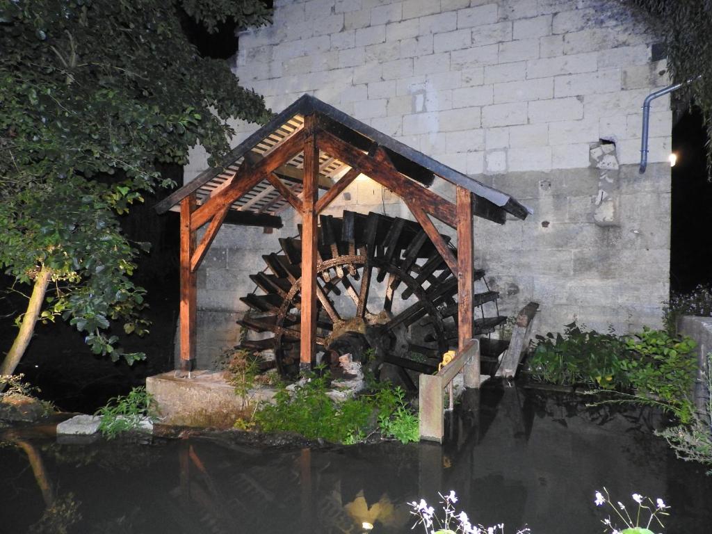 une roue à eau en bois assise au milieu d'un étang dans l'établissement Le Moulin De Saussaye, à Crouzilles