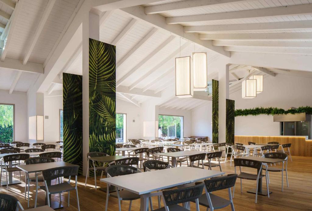 a dining room with tables and chairs and plants at VOI Marsa Siclà Essentia in Sampieri