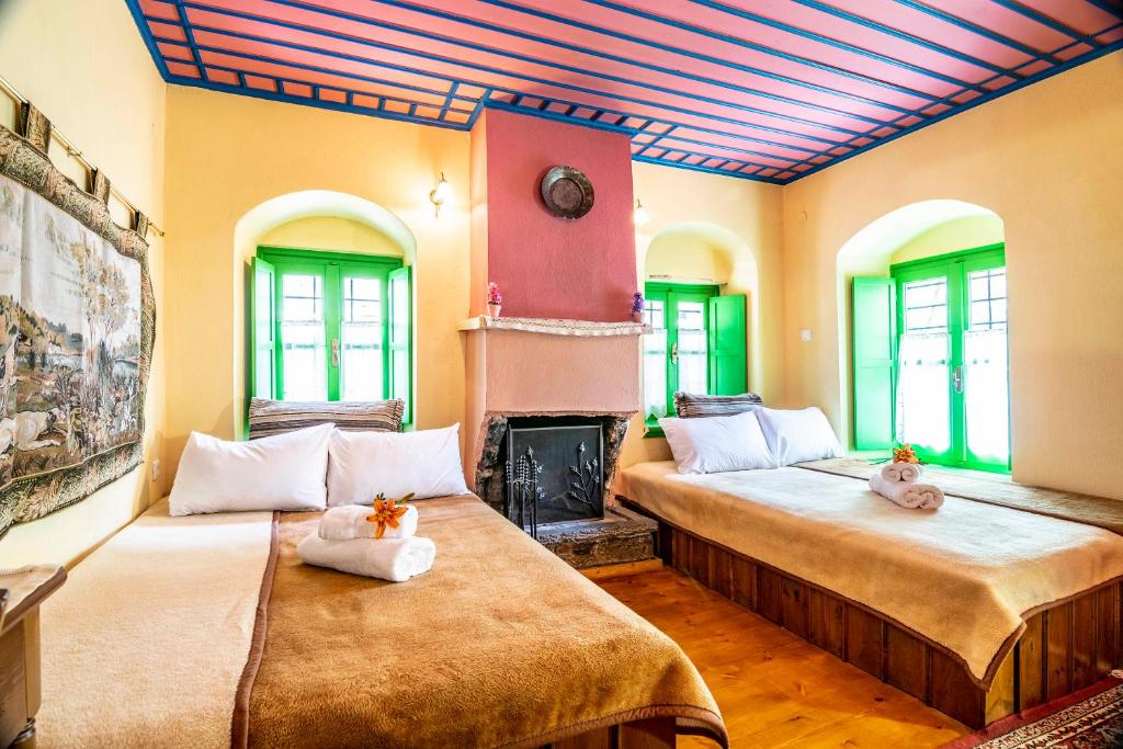 two beds in a room with a fireplace at Morfeas Guesthouse in Papigko