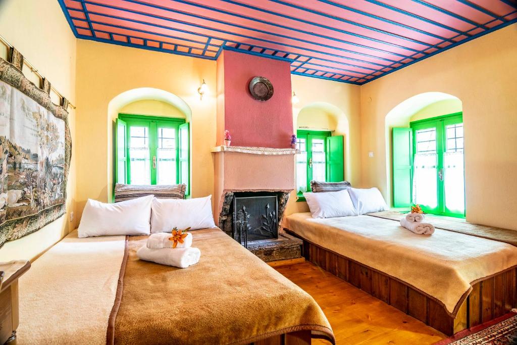 two beds in a room with a fireplace at Morfeas Guesthouse in Papingo