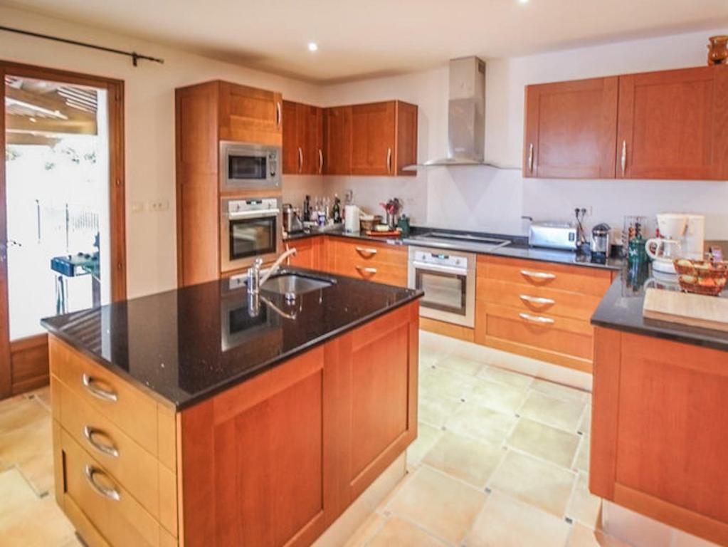 a kitchen with wooden cabinets and a black counter top at La Bastide des Cairns in Seillans