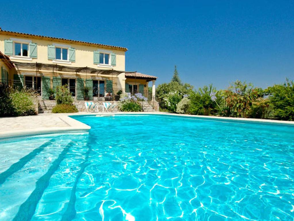 a large blue swimming pool in front of a house at La Bastide des Cairns in Seillans