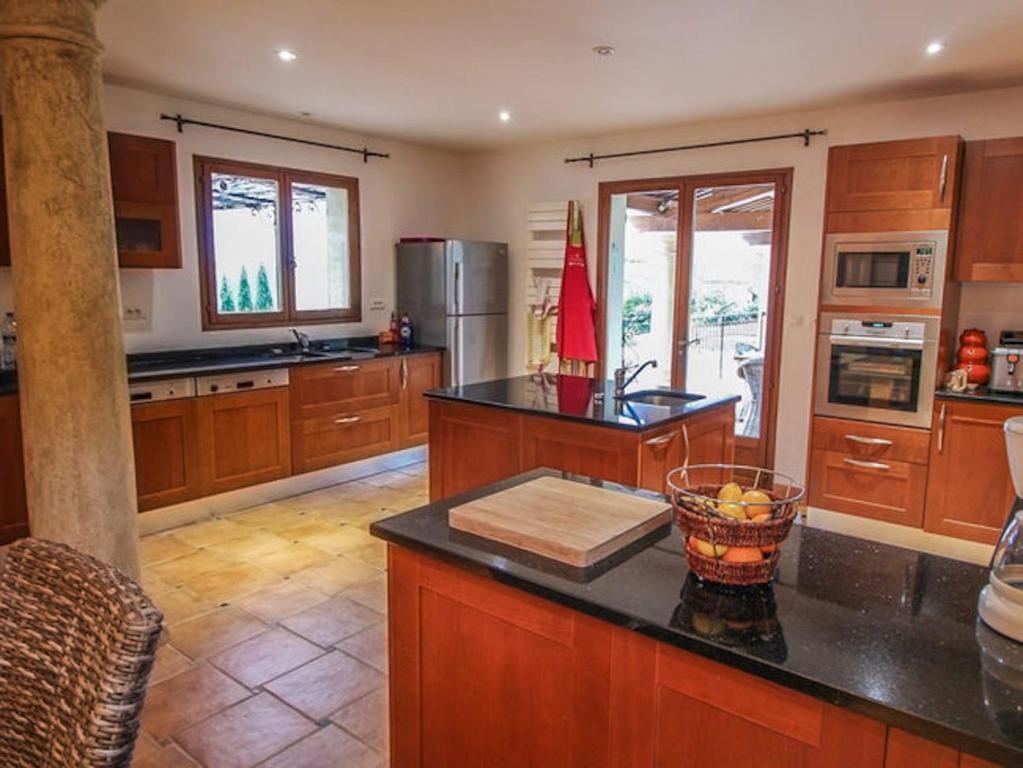 a large kitchen with wooden cabinets and a counter top at La Bastide des Cairns in Seillans