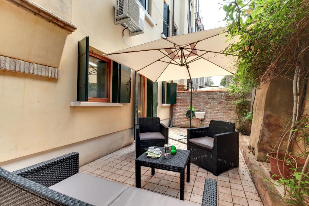 un patio con 2 sillas y una sombrilla en Cannaregio - Venice Style Apartments, en Venecia