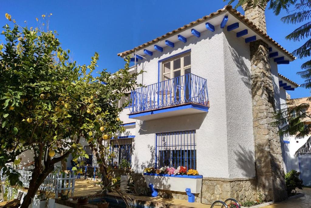 a white house with a balcony and a tree at Blue Castle GuestHouse in Málaga
