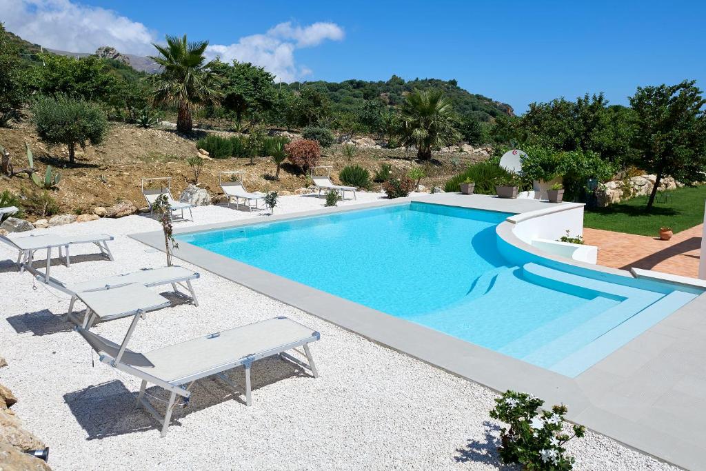a swimming pool with two lounge chairs next to it at Tenute Plaia Agriturismo in Scopello
