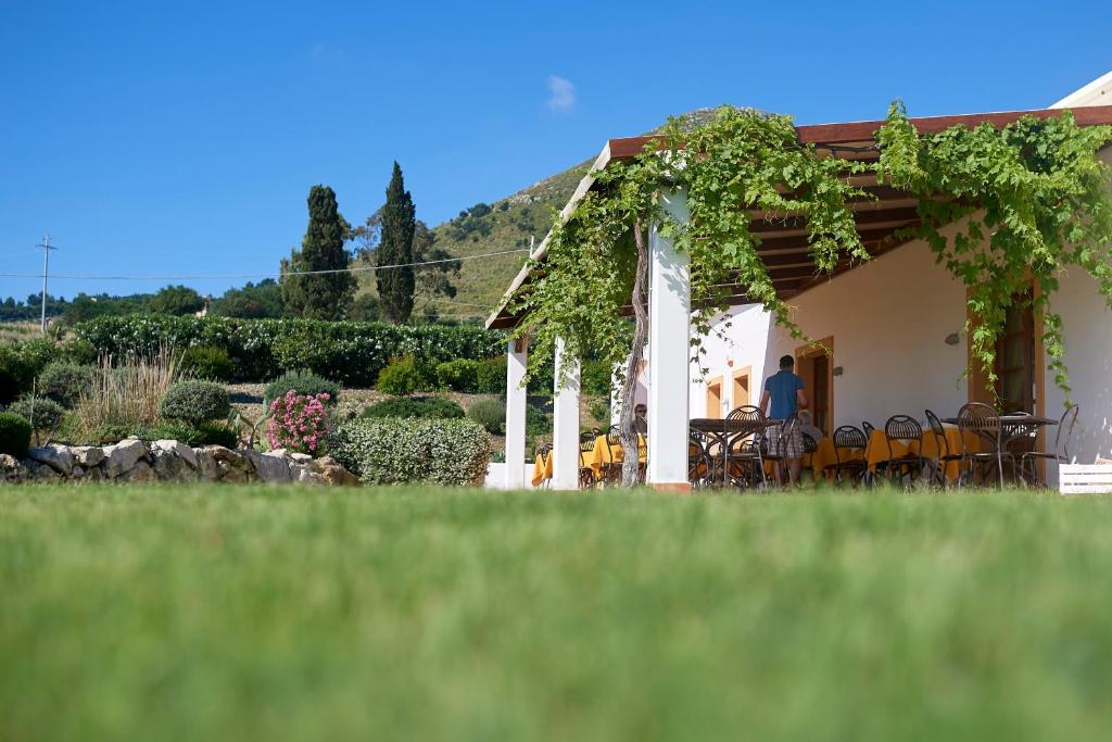 a person sitting at a table outside of a house at Tenute Plaia Agriturismo in Scopello