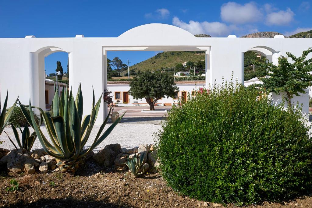 a white house with some plants in a yard at Tenute Plaia Agriturismo in Scopello