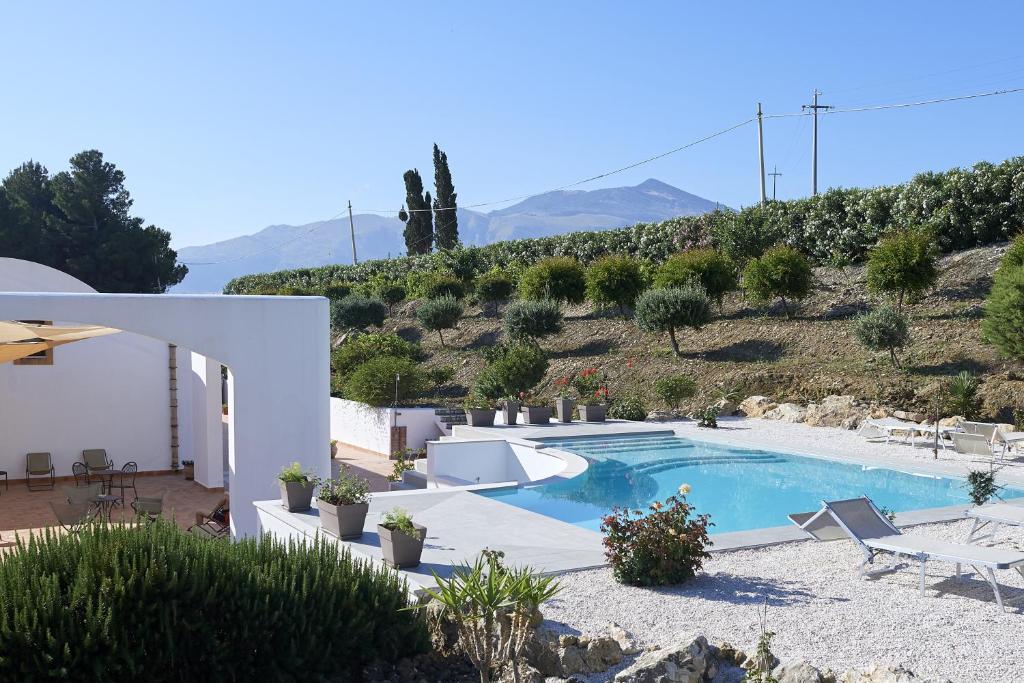 a villa with a swimming pool and a hill at Tenute Plaia Agriturismo in Scopello
