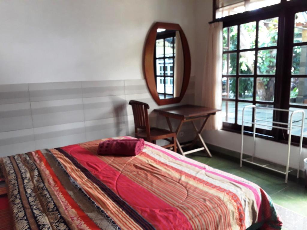 a bedroom with a bed and a mirror and a chair at Manuh Guest House in Nusa Dua