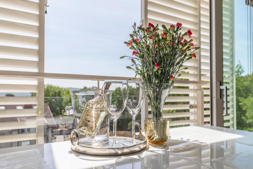 a table with wine glasses and a vase with flowers at Apartament Prestige & Sea Playa Baltis 63 in Międzyzdroje