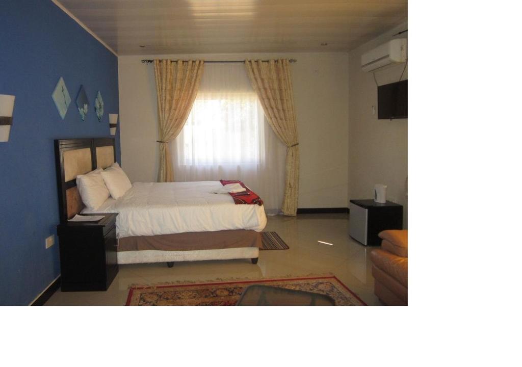um quarto com uma cama e uma janela em Royal Olympia Lodges and Safaris Livingstone em Livingstone
