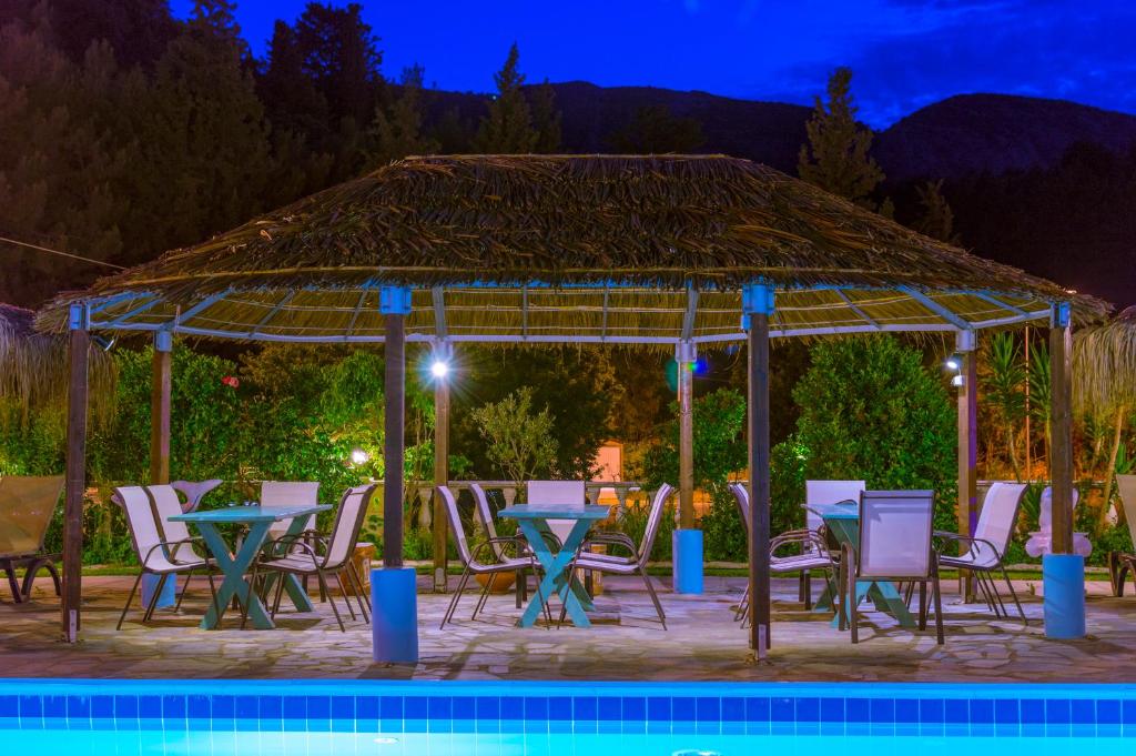 a gazebo with tables and chairs next to a pool at Kokkari Beach Hotel in Kokkari