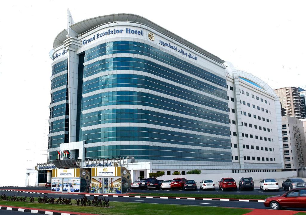 een groot gebouw met auto's geparkeerd voor het bij Grand Excelsior Hotel - Bur Dubai in Dubai