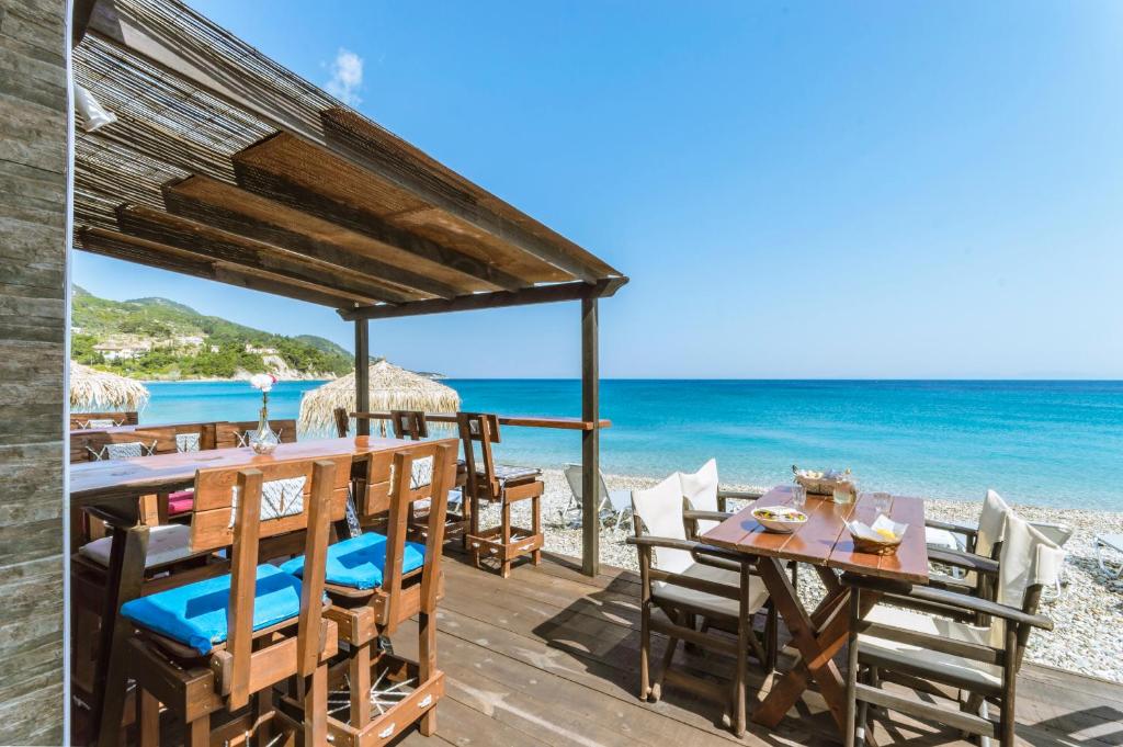 a wooden deck with tables and chairs on the beach at Kokkari Beach Hotel in Kokkari