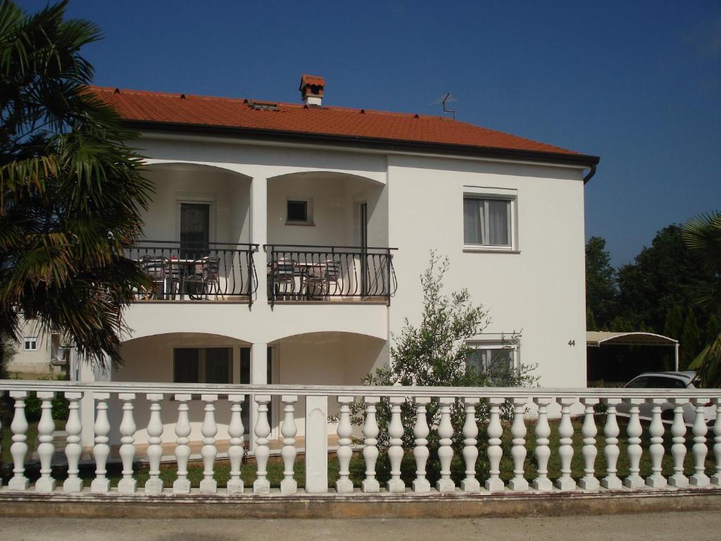 een wit huis met een balkon en een hek bij Apartmani i soba Mia Poreč in Poreč