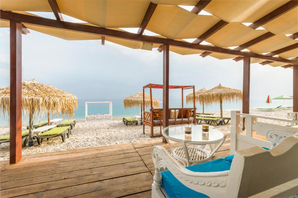 a beach with a table and chairs and the ocean at Kokkari Beach Hotel in Kokkari