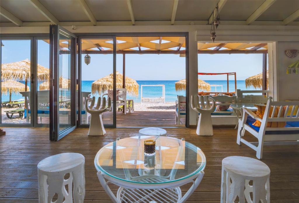 a room with a glass table and chairs and the beach at Kokkari Beach Hotel in Kokkari