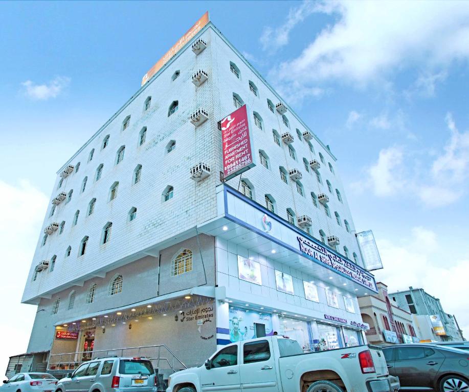 a large white building with cars parked in front of it at Star Emirates Furnished Apartments 2 in Salalah