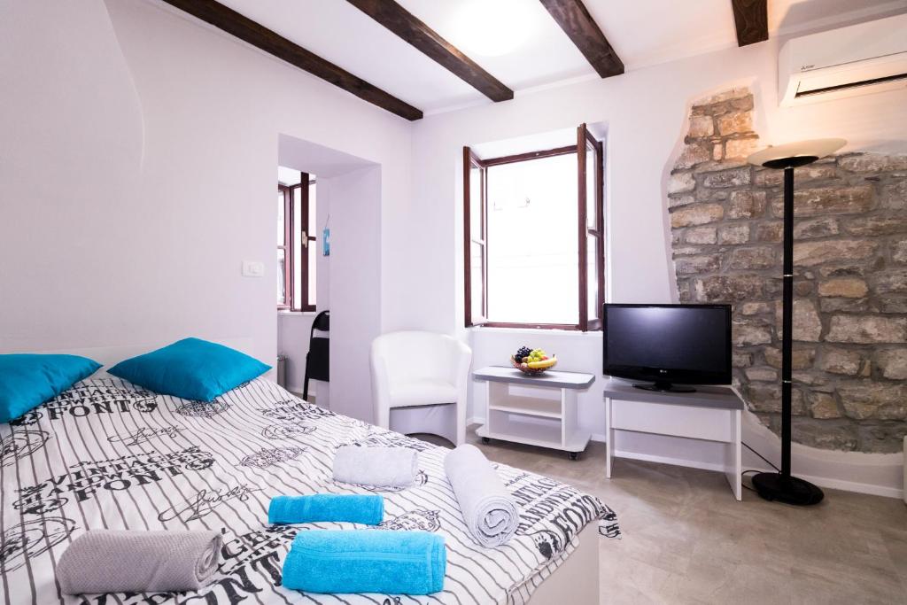 a white bedroom with a large bed and a tv at Apartments Bella Tara in Piran