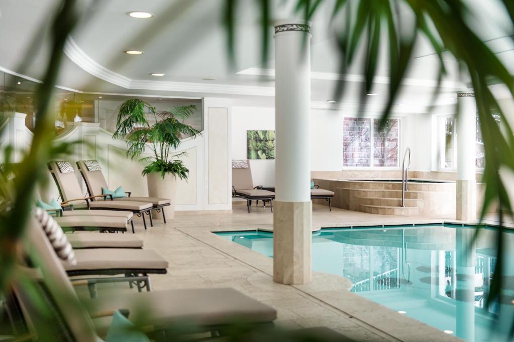 a lobby with a pool and chairs and a tub at Hotel Grones in Ortisei