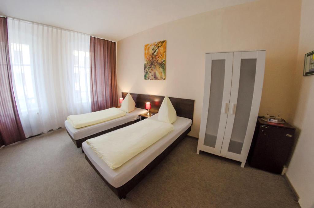 a hotel room with two beds and a window at Hotel-Pension Victoria in Berlin