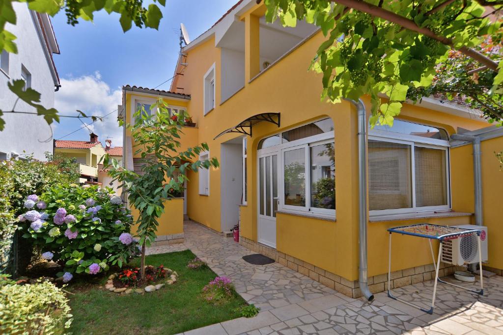 una casa amarilla con una mesa delante en Apartments Milena 436, en Fažana
