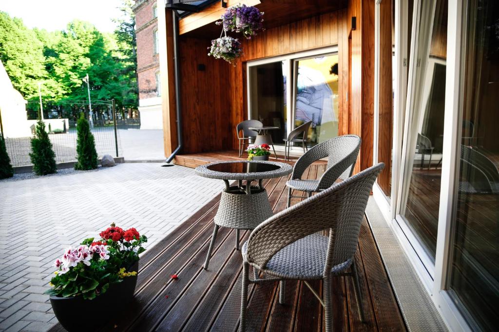 um alpendre com cadeiras, uma mesa e flores em Dönhoff Residence em Pärnu