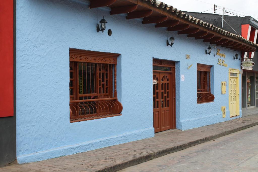 un edificio azul con puertas de madera en una calle en Hospedaje La Casona, en Tabio