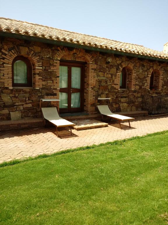 two benches sitting in front of a stone building at Hotel Corsaro Nero in Portu Maga