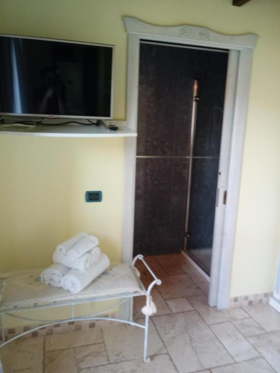 a room with a tv and a chair with towels at Hotel Corsaro Nero in Portu Maga