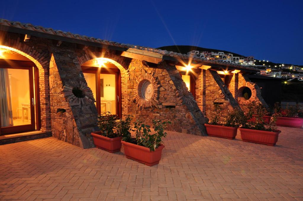 a stone building with potted plants on it at night at Hotel Corsaro Nero in Portu Maga