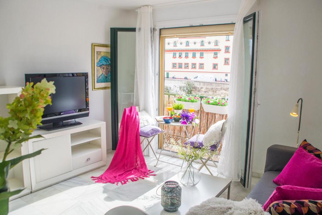 a living room with a couch and a tv at 4Seasons La Rosaleda Apartment in Málaga