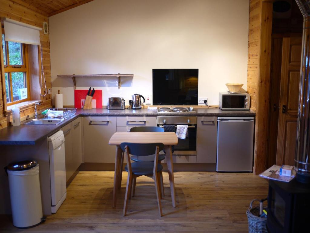 uma cozinha com uma pequena mesa e um fogão em Dulnain em Aviemore